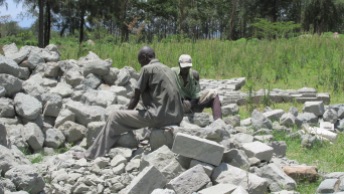 Two men carving a pile of rocks.